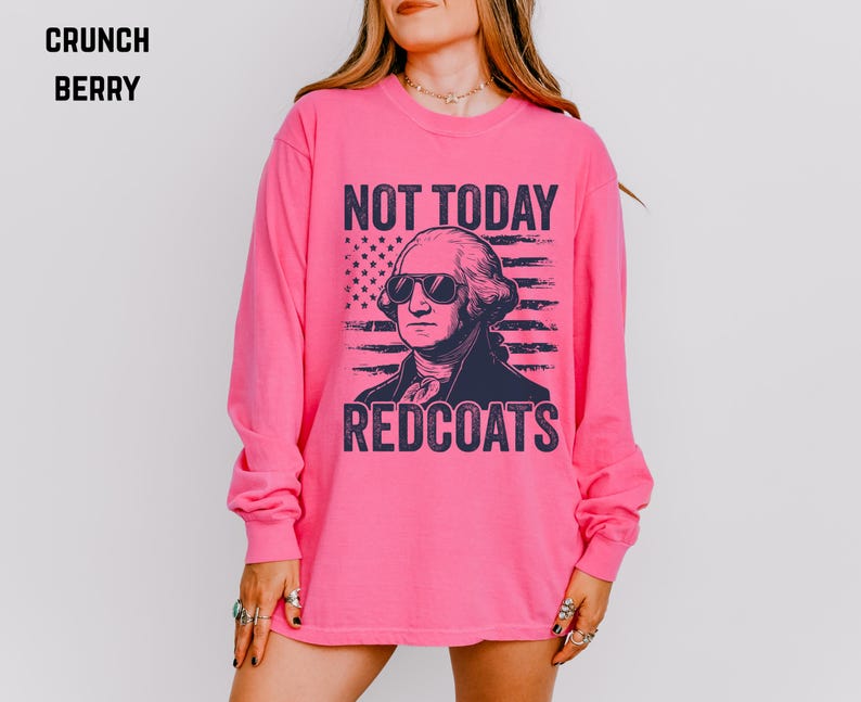 May include: A long-sleeved, bright pink shirt with a graphic of George Washington wearing sunglasses. The text "NOT TODAY REDCOATS" is printed above and below the image of the American flag.