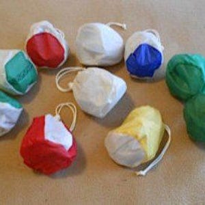 May include: A collection of small, colorful drawstring bags. The bags are made of a lightweight material and come in various colors, including red, green, blue, and yellow. Each bag has a white drawstring closure.