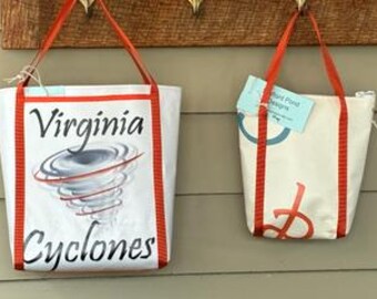 Puede incluir: Dos bolsas de mano con correas rojas. La bolsa más grande es blanca con un diseño de tornado gris y rojo y el texto "Virginia Cyclones". La bolsa más pequeña es blanca con un diseño de círculo azul y verde y el texto "Wild Pond Designs".