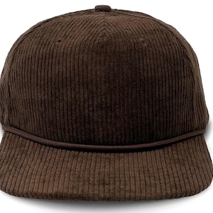 Puede incluir: Una gorra de béisbol de pana marrón con una banda elástica negra alrededor del borde.