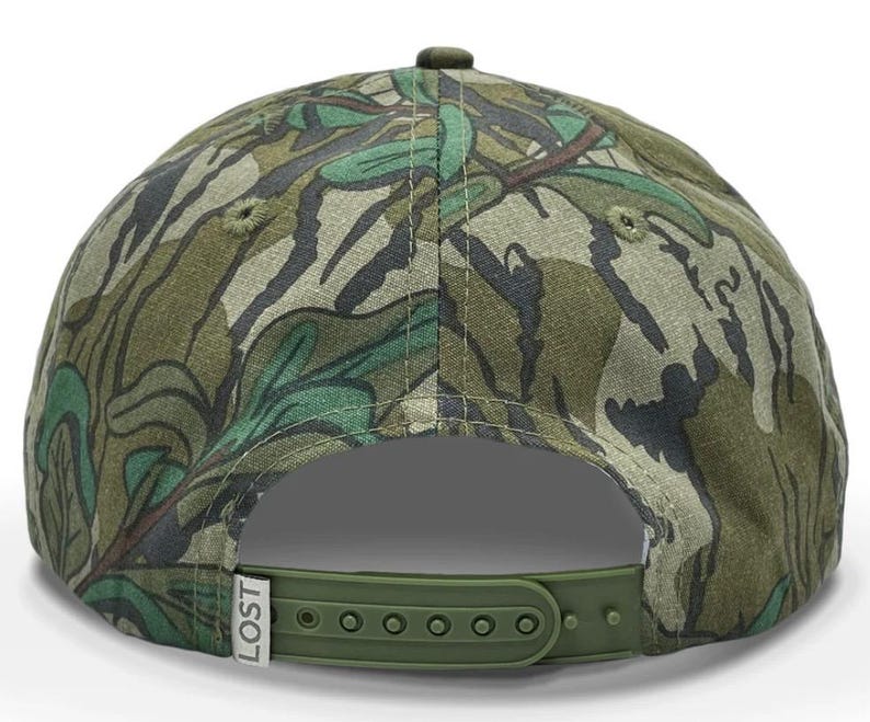 May include: A green, brown, and black camouflage baseball cap with an adjustable strap and the word "LOST" printed on the side.