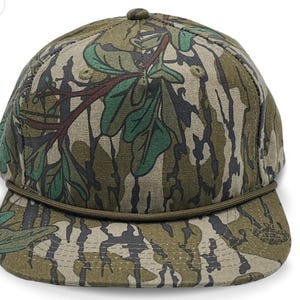 May include: A camouflage baseball cap with a green, brown, and black pattern. The cap has a brown brim and a green strap.