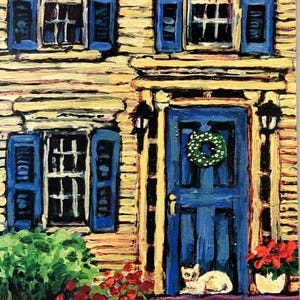 Könnte beinhalten: Acrylbild einer Hausfassade mit blauen Fensterläden und Tür. Eine weiße Katze ruht auf der Veranda. Rote Blumen und grüne Büsche umrahmen den Eingang. Ein grüner Kranz hängt an der Tür.