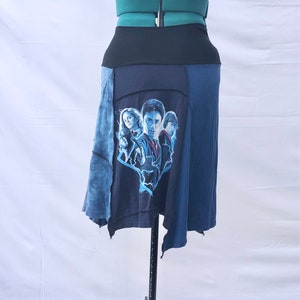 May include: A blue and black patchwork skirt with a Harry Potter graphic print. The skirt has a black waistband and a frayed hem.