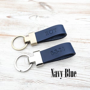 May include: Two navy blue leather keychains with metal hardware. One keychain features a gold-tone ring and the embossed text R heart T. The other keychain features a silver-tone ring and the embossed text 6-3-24. The text Navy Blue is visible.