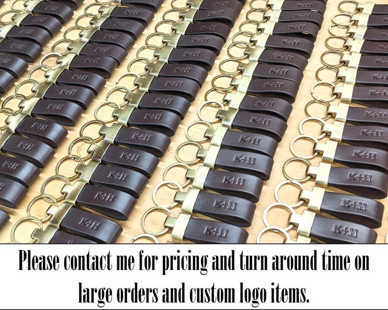 May include: A large collection of dark brown leather keychains arranged in rows. Each keychain features a brass-toned metal ring and a rectangular leather strap embossed with the letters K+H. The text below reads: Please contact me for pricing and turn around time on large orders and custom logo items.