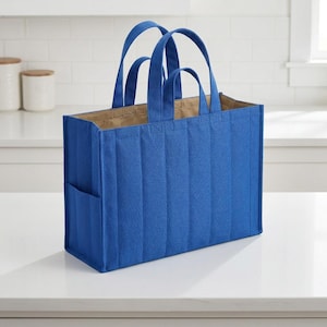 May include: A rectangular tote bag in a vibrant royal blue color featuring a vertical quilted pattern. The bag has two sets of handles of varying lengths, a structured base, and an open top design with a tan interior lining and side pockets.