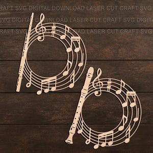 May include: Two laser-cut wooden musical decorations. Each features a flute and a circular design of musical notes and a treble clef. The background is a dark brown wood grain.