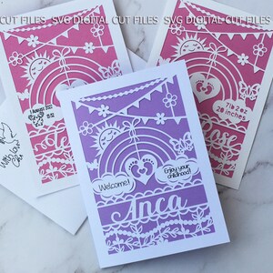 May include: A set of laser-cut paper cards in shades of pink and purple. The designs include rainbows, suns, and floral patterns. One card is personalized with the name "Anca" and the phrase "Enjoy your childhood!" Other cards include baby details.
