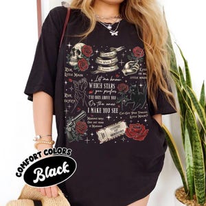 K&ouml;nnte beinhalten: Schwarzes Grafik-T-Shirt mit Totenkopf, Rosen, einer Katze und Text. Der Text enth&auml;lt S&auml;tze wie &bdquo;Run, Little Mouse&ldquo; und &bdquo;Which Stars You Prefer&ldquo;. Das Shirt zeigt auch eine Pistole und ein Ticket mit &bdquo;House of Mirrors&ldquo;.