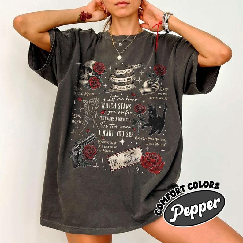 K&ouml;nnte beinhalten: Dunkelgraues T-Shirt mit einem Grafikdesign mit einem Totenkopf, Rosen, einer Katze und Text. Der Text enth&auml;lt S&auml;tze wie &bdquo;Run, Little Mouse&ldquo; und &bdquo;Let me know which stars you prefer&ldquo;. Das Shirt hat einen Vintage-Look.