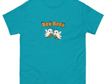 May include: A turquoise t-shirt featuring the text "Boo Bees" above a graphic of two cartoon bees dressed as ghosts. The bees are white with black and yellow stripes, holding small pumpkin-shaped containers. The shirt is made of a soft material.