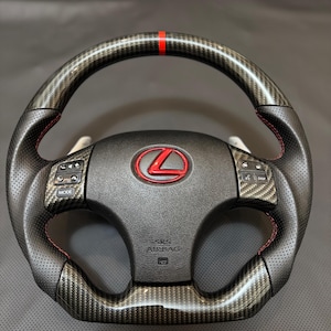 May include: A black leather steering wheel with a carbon fiber wrap and red stitching. The steering wheel has a red stripe at the top and a Lexus logo in the center. The steering wheel also has controls for mode, disp, and other functions. The text "SRS AIRBAG" is printed on the steering wheel.