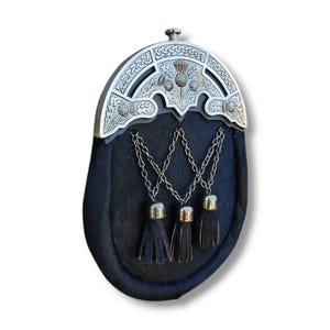 Pu&ograve; includere: Un sporran in pelle nera con un cantle argentato con disegni di cardi e nodi celtici. Lo sporran ha tre nappe nere appese a catene d'argento. Questo tradizionale accessorio scozzese viene utilizzato per contenere oggetti personali.