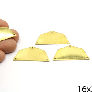 May include: Four gold-colored metal pendant blanks in a half-moon shape, each with three small holes for attaching to other components. One is held by a hand. The dimensions are 16x32mm.