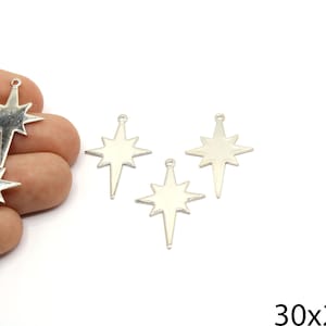 May include: Silver-colored star charms, each with eight points and a small loop at the top for hanging. The charms are approximately 1.2 inches long and 0.8 inches wide. The image shows several charms, some held in a hand.