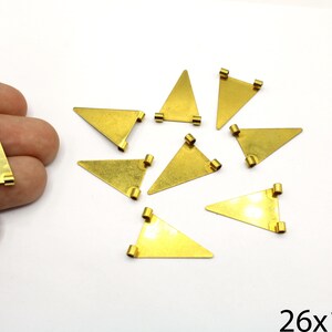 May include: Gold-coloured metal triangle charms, each with small loops at the corners. The charms are approximately 2.6 cm by 1.7 cm. The charms are displayed on a white surface.