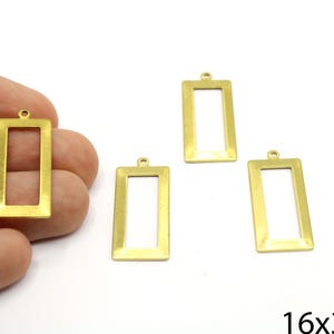 May include: Four gold-colored metal rectangular frames with a loop at the top. The frames are 16 mm by 32 mm.