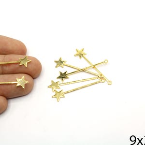 May include: Gold-colored star charms with a small loop at the end of the bar. The charms are in the shape of a star on a stick. The image also includes the dimensions of the charms, which are 9mm x 39mm.