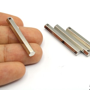 May include: Silver-colored metal bar pendants, approximately 2 inches long, with a hexagonal shape and a hole at one end. Several pendants are displayed on a white background, suitable for jewelry making.