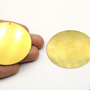May include: Two gold-colored metal circles with a hole in the center. Each circle is approximately 52 mm in diameter.