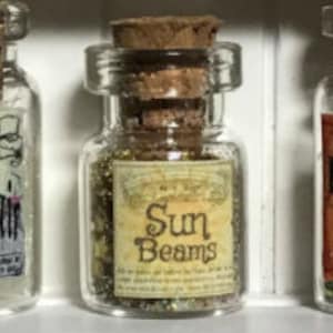 Könnte beinhalten: Drei kleine Glasflaschen mit Korken und Etiketten. Die mittlere Flasche ist mit "Sun Beams" beschriftet und enthält goldenen Glitzer. Die anderen Flaschen sind mit "Hair" und "Rain Salt" beschriftet.