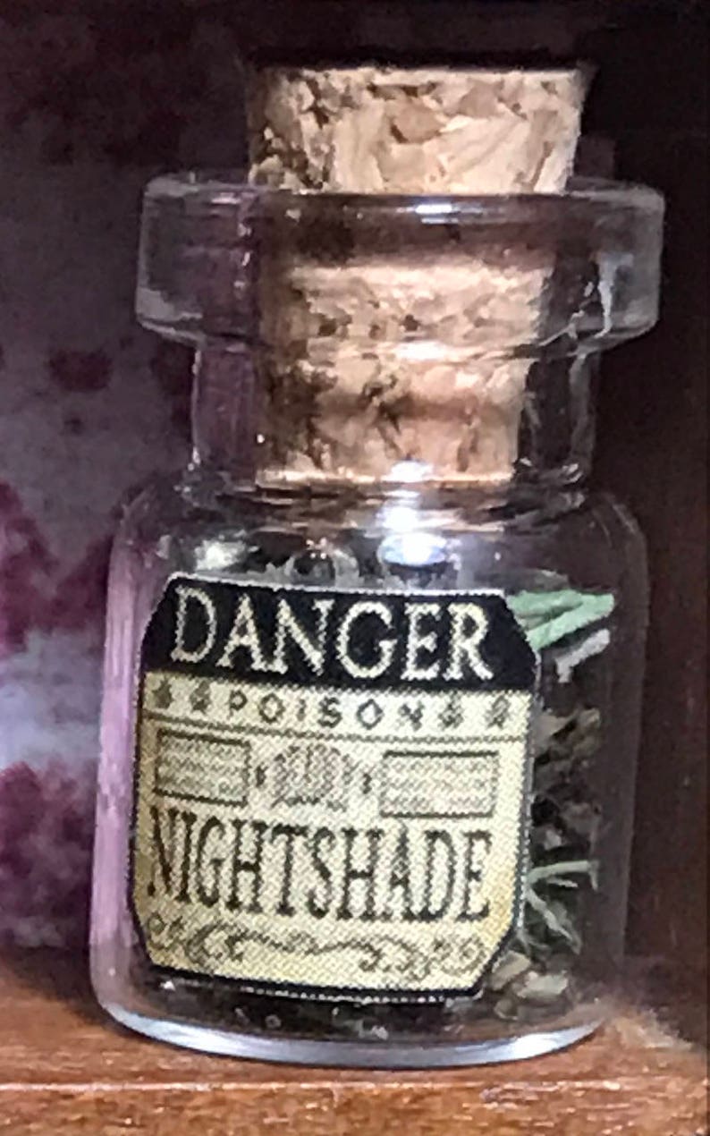 May include: A small, clear glass bottle with a cork stopper. The label reads "DANGER POISON NIGHTSHADE" in black and gold lettering. The bottle contains dried herbs.