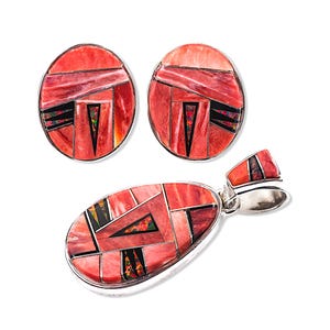 Könnte beinhalten: Ein Schmuckset mit Anhänger und passenden Ohrringen. Das Set hat ein geometrisches Design mit roten, schwarzen und irisierenden Akzenten in Silbermetall. Die Ohrringe sind oval, und der Anhänger ist tropfenförmig.