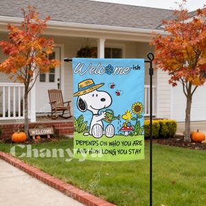 May include: A rectangular garden flag with a light blue sky and green grass background. It features Snoopy wearing a straw hat and watering a flower with Woodstock nearby. The text reads "Welcome-ish" and "DEPENDS ON WHO YOU ARE AND HOW LONG YOU STAY".