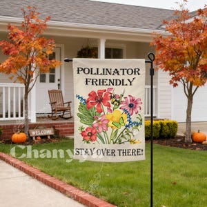 May include: A beige garden flag with the words "POLLINATOR FRIENDLY" and "STAY OVER THERE!" in black. The flag features a colourful floral design with red, pink, yellow, and purple flowers, along with butterflies and bees. The flag is displayed in a front garden.
