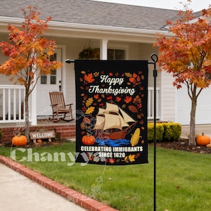 May include: Black Thanksgiving garden flag with a ship illustration, pumpkins, and corn. Text reads "Happy Thanksgiving" and "Celebrating Immigrants Since 1620". Autumn leaves surround the design. The flag is displayed outdoors.