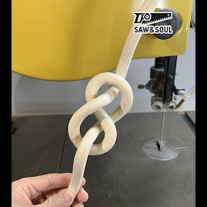 May include: A light-colored wooden knot, possibly a decorative element or part of a larger woodworking project. The knot is intricately formed, with smooth, curved lines. The image includes the text "SAW & SOUL".
