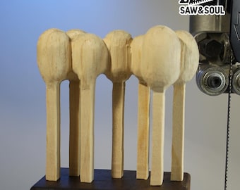 May include: A handcrafted wooden sculpture featuring a series of stylized, rounded shapes atop slender, rectangular supports. The natural wood grain is visible. The sculpture is mounted on a dark, rectangular base. The logo "SAW&SOUL" is visible in the upper right corner.