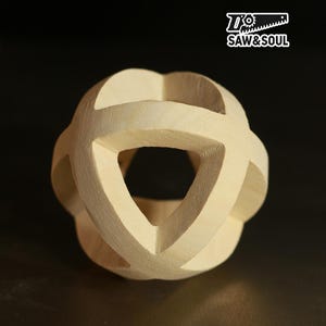 May include: A light-colored wooden sphere with a geometric design. The sphere has intersecting curved lines that create open spaces. The logo "Saw & Soul" is in the upper right corner.