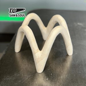 以下が含まれることがあります： ユニークな波状のデザインのウッドスタンド。スタンドは明るい色の木でできており、滑らかな仕上がりです。