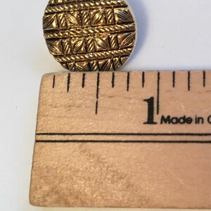 May include: A gold-colored button with a woven pattern, measuring approximately 1 inch in diameter.