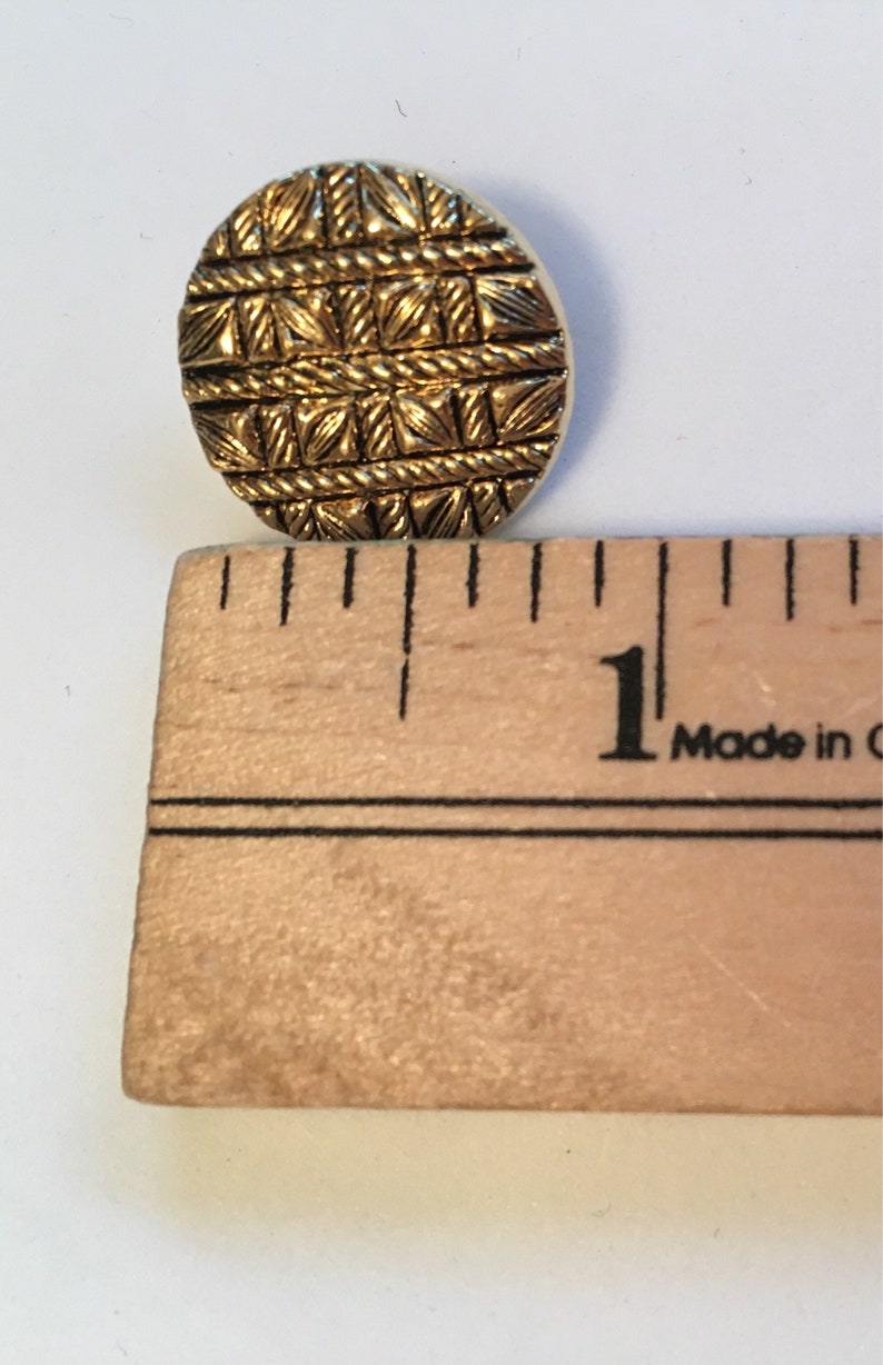 May include: A gold-colored button with a woven pattern, measuring approximately 1 inch in diameter.