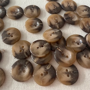 May include: A collection of brown and white swirl patterned buttons. The buttons have two holes and are made of a smooth, shiny material.