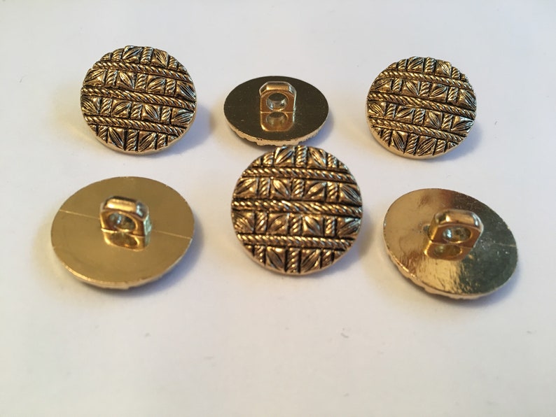 May include: Six gold-colored buttons with a woven pattern. The buttons have a shank on the back.