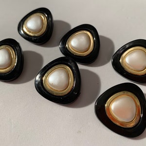Puede incluir: Seis botones negros en forma de triángulo con un borde dorado y un centro blanco perlado.