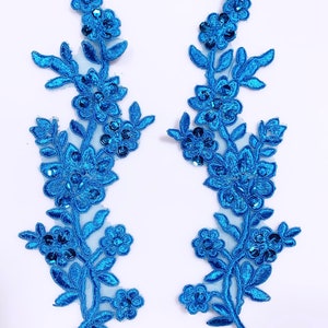 May include: Two blue floral appliques with sequins. Each applique features a delicate floral design with leaves and flowers.