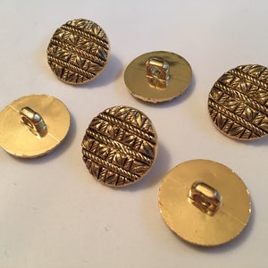 May include: Five gold-colored buttons with a raised, woven design. The buttons have a shank on the back.