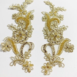 May include: Two gold floral lace appliques with beaded details. The appliques are perfect for adding a touch of elegance to any project.