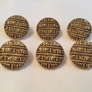 May include: Six gold-colored round buttons with a woven pattern. The buttons are about 1 inch in diameter.