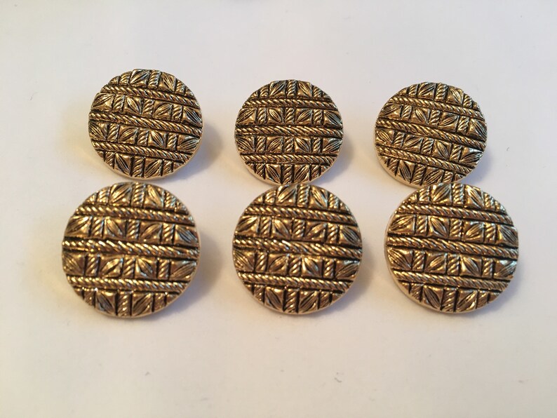 May include: Six gold-colored round buttons with a woven pattern. The buttons are about 1 inch in diameter.