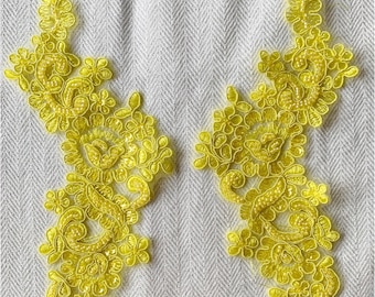 May include: Two yellow floral lace appliques with a beaded design on a white background.