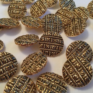 May include: A collection of gold-toned buttons with a woven pattern. The buttons are round and have a raised design.