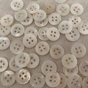 May include: A collection of white, round, four-hole shell buttons.