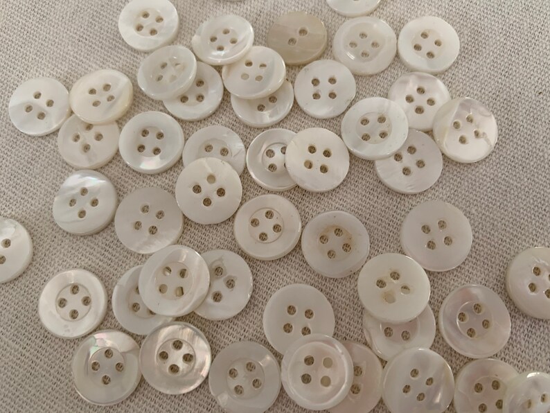 May include: A collection of white, round, four-hole shell buttons.