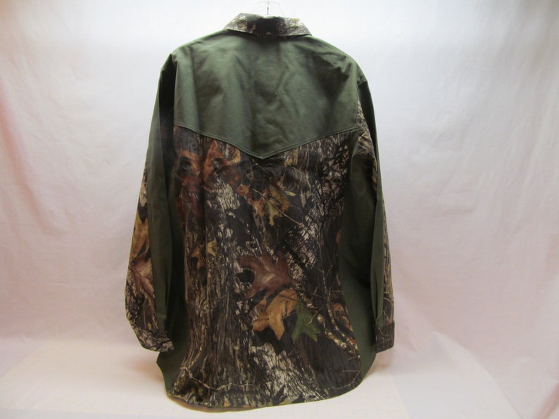 Puede incluir: Una camisa de manga larga con botones con un patr&oacute;n de camuflaje en la mitad inferior y un color verde s&oacute;lido en la mitad superior.